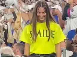 Actriz de la campaña de Smile sonriendo de forma inquietante en las gradas de un estadio